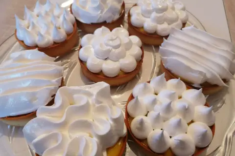 Plateau de tartelettes garnies de crème au citron et couronnées de meringue italienne, une œuvre de conservation gourmande.