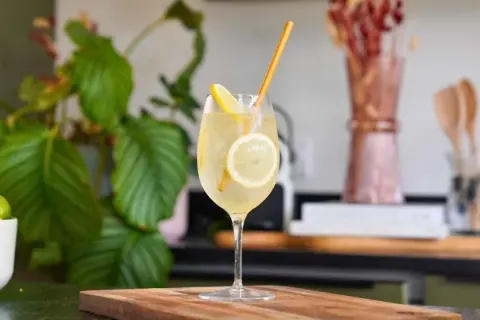 Un cocktail pétillant à la limoncello, garni de rondelles de citron et d'une paille dorée. Une recette rafraîchissante pour l'été.