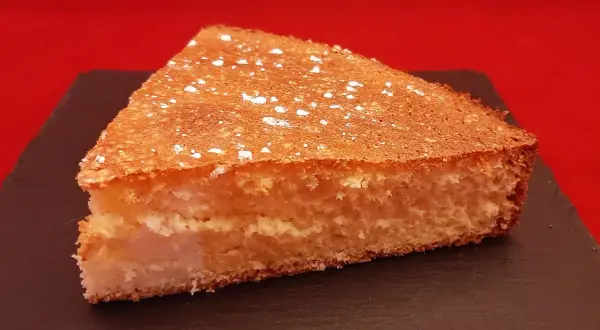 Tranche de gâteau de Savoie aérien, saupoudrée de sucre glace. Une recette facile avec fécule pour un dessert léger.