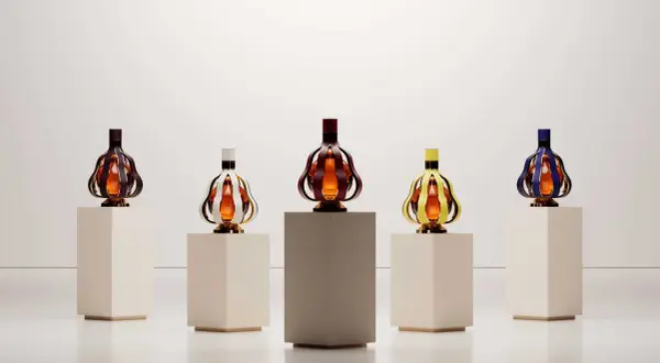 Cinq bouteilles de vin aux formes originales, aux couleurs vives, présentées sur des socles. Une nouvelle tendance vin qui allie art et dégustation.
