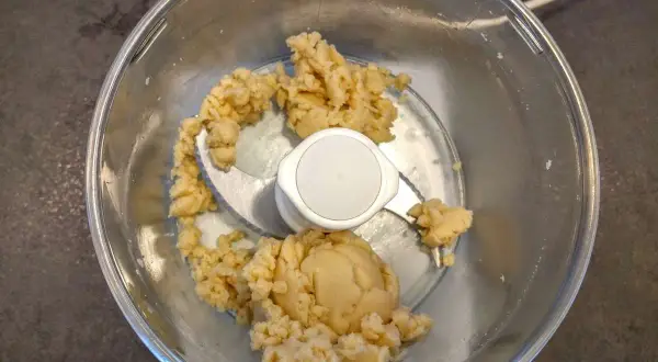 Pâte d'amande maison dans un robot culinaire, prête à être façonnée en délicieuses friandises.