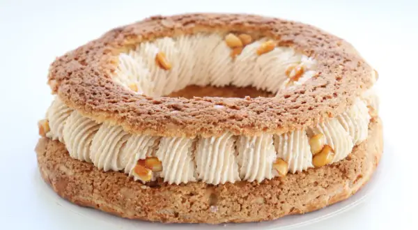 Un Paris-Brest rond, garni d'une crème onctueuse et parsemé de morceaux de praliné cacahuète croquant.
