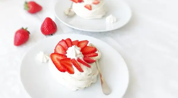 Deux pavlovas ornés de fraises et de crème fouettée, une touche de curd mangue passion pour l'exotisme.