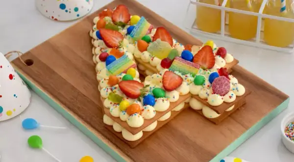 Un délicieux number cake 10 ans, décoré de fraises, bonbons arc-en-ciel et pépites colorées, prêt pour une fête d'anniversaire.