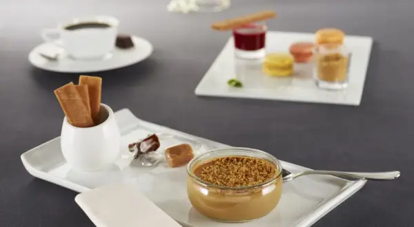 Un café gourmand avec diverses mignardises : crème dessert, macarons, biscuits, chocolats. Parfaites pour des recettes de mignardises pour café gourmand.