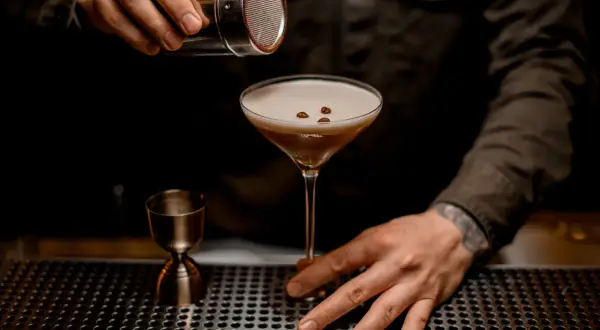 Un barman termine la préparation du cocktail du moment, saupoudrant des grains de café sur la mousse onctueuse d'un verre à martini.