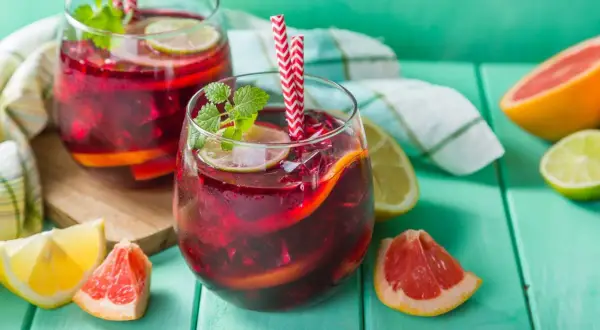 Deux verres de sangria rouge vif, garnis de fruits et de menthe, prêts à être dégustés. Le vin pour sangria est parfait pour les journées chaudes.
