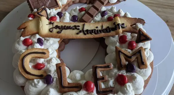 Gâteau décoré de crème fouettée, biscuits en forme de lettres formant "CLEM", chocolats et bonbons. Quelle crème pour recouvrir un gâteau, celle-ci est parfaite !