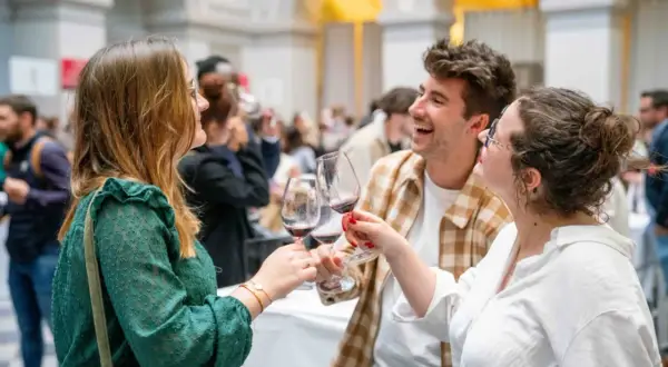 Trois amis trinquent avec des verres de vin rouge, célébrant peut-être la vin primeur définition. Ambiance festive.