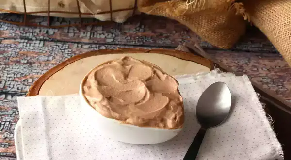 Une cuillère attend patiemment à côté d'un bol rempli d'une onctueuse ganache Nutella, prête à être dégustée.