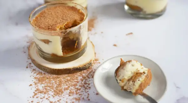 Délicieux tiramisu, un dessert sans cuisson, servi dans des verres, saupoudré de cacao. Une cuillère en est prête à être dégustée.