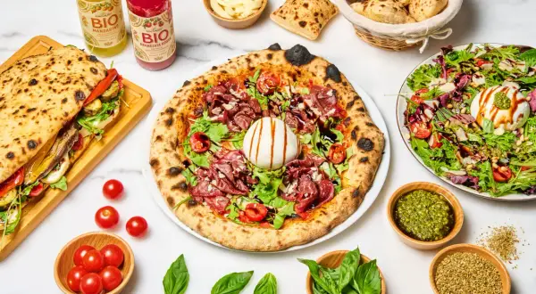 Une pizza savoureuse, un sandwich garni, une salade fraîche et des boissons. Quel vin avec pizza ? Un repas italien parfait pour partager.