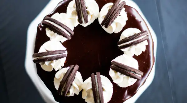 Gâteau au chocolat glacé, décoré de crème fouettée et de biscuits Oreo. Un délice pour les amateurs de layer cake Oreo.