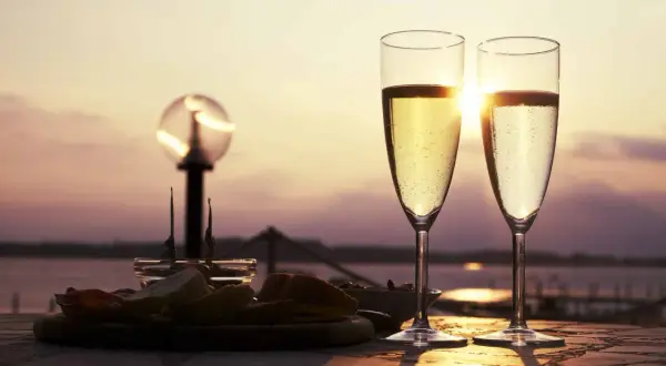 Deux flûtes de ratafia de Champagne pétillant, servies avec des amuse-bouches au coucher du soleil. Parfait pour savoir comment le boire.