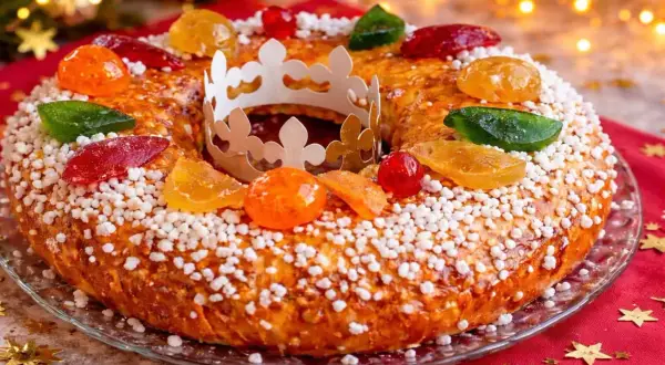 Gâteau des Rois orné de fruits confits et d'une couronne en papier, prêt à être dégusté. Une belle idée pour une recette de gâteau des rois festive.