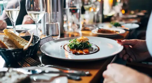 Un dîner élégant avec du vin pétillant, du saumon fumé et du pain frais. Une table dressée pour une occasion spéciale, avec des fruits de mer et des boissons.