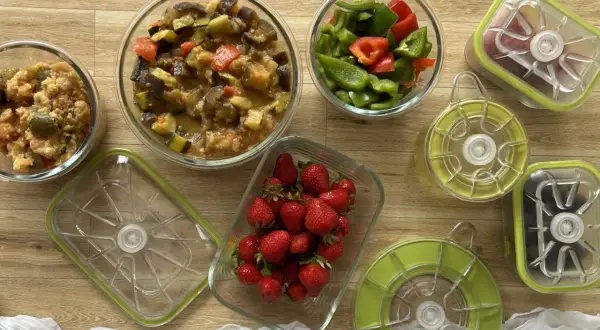 Préparation pour le batch cooking du goûter : ratatouille, poivrons coupés, fraises et autres ingrédients dans des boîtes hermétiques.