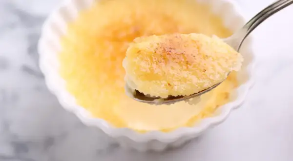 Une cuillère de semoule au lait au four, dorée et caramélisée, prête à être dégustée.