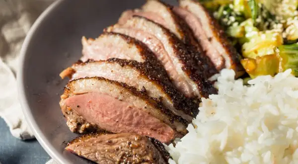 Tranches de magret de canard, riz blanc et légumes. Un plat savoureux qui invite à se demander : que boire avec du magret de canard ?