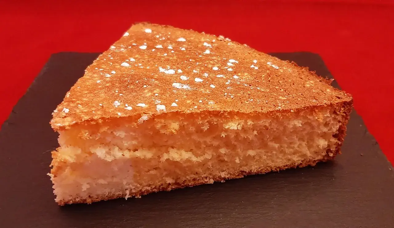 Tranche de gâteau de Savoie aérien, saupoudrée de sucre glace. Une recette facile avec fécule pour un dessert léger.