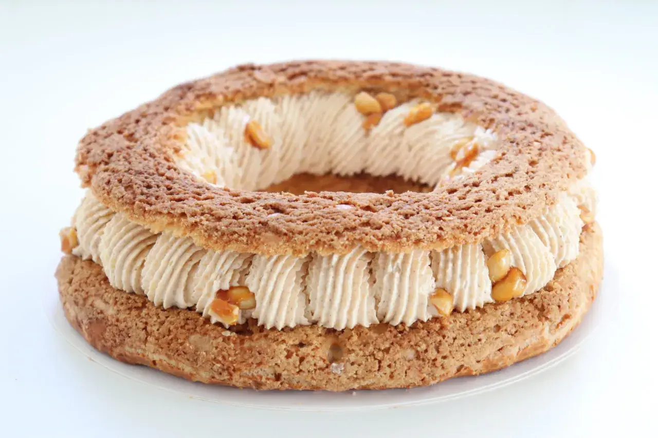 Un Paris-Brest rond, garni d'une crème onctueuse et parsemé de morceaux de praliné cacahuète croquant.