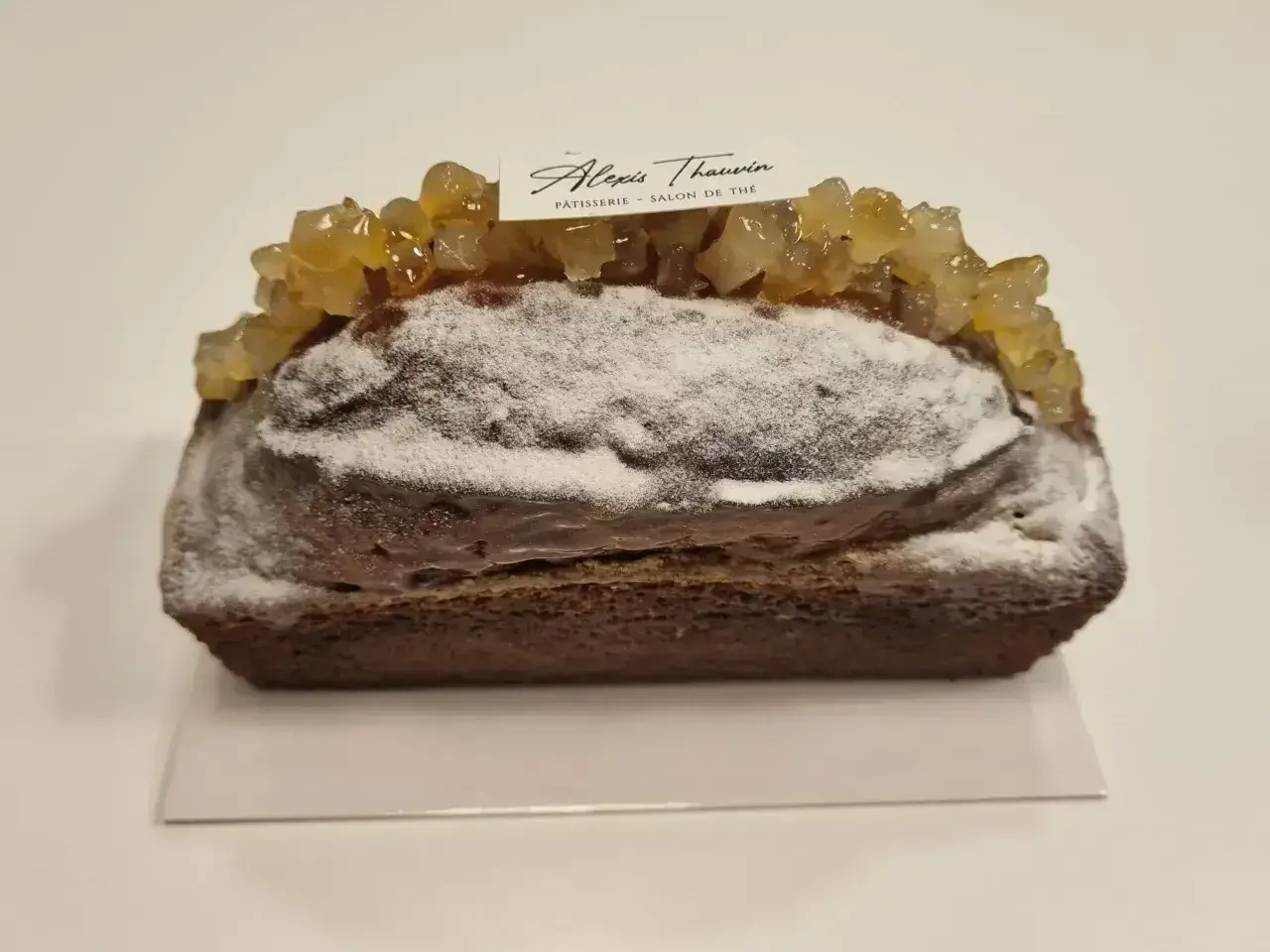 Gâteau moelleux au citron, saupoudré de sucre glace et garni de fruits confits. Une pâtisserie Alexis Thauvin.