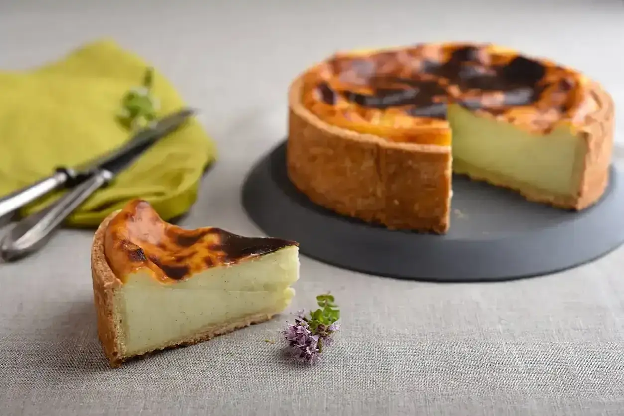 Un flan pâtissier onctueux sur une pâte feuilletée ou brisée dorée, avec une part coupée. Un délice à déguster !
