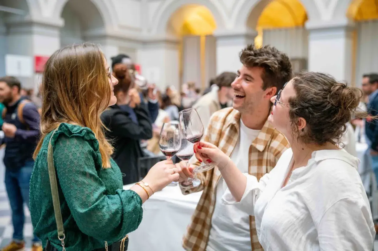 Trois amis trinquent avec des verres de vin rouge, célébrant peut-être la vin primeur définition. Ambiance festive.