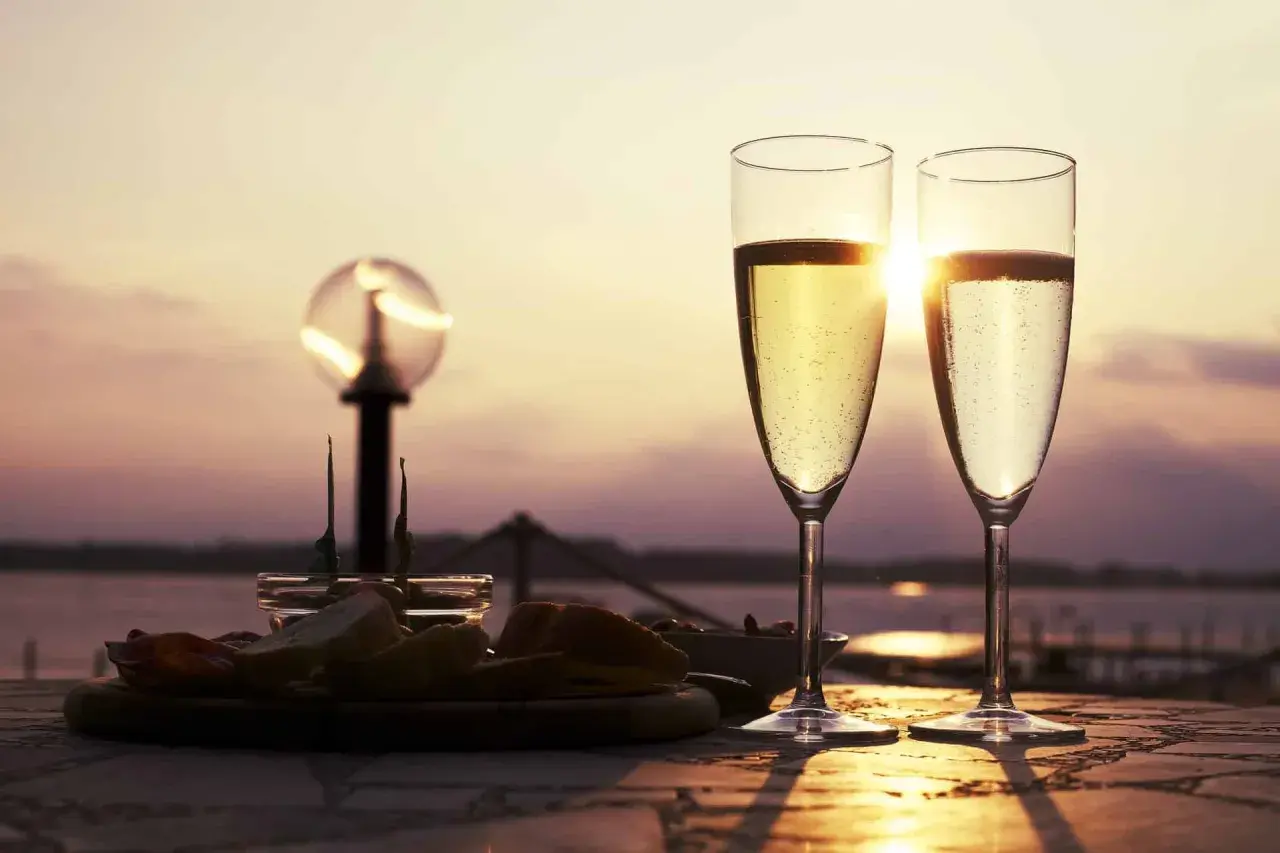 Deux flûtes de ratafia de Champagne pétillant, servies avec des amuse-bouches au coucher du soleil. Parfait pour savoir comment le boire.