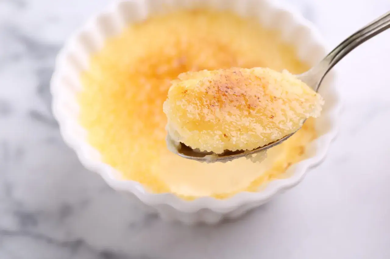 Une cuillère de semoule au lait au four, dorée et caramélisée, prête à être dégustée.