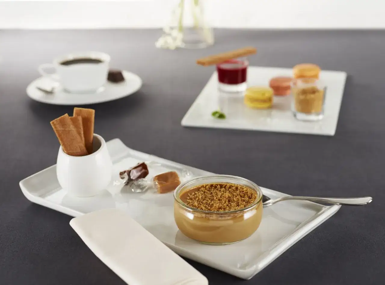 Un café gourmand avec diverses mignardises : verrine caramel, macarons, bonbons, tuiles croustillantes. Idéal pour des recettes de mignardises pour café gourmand.