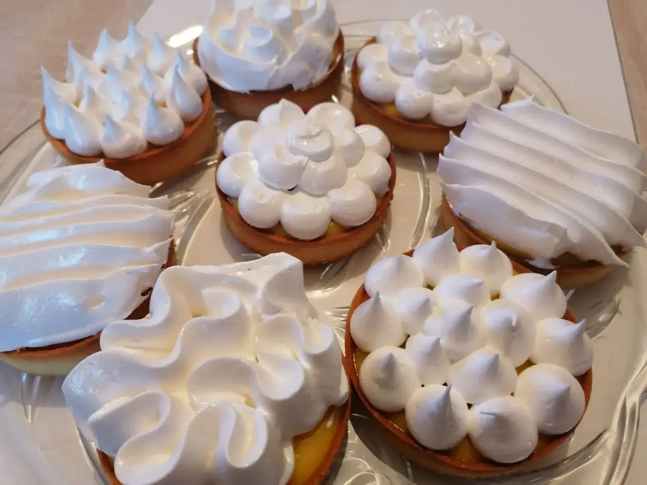 Plusieurs tartelettes au citron garnies de meringue italienne, prêtes pour la conservation.