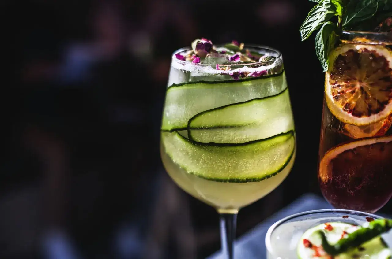 Un cocktail concombre rafraîchissant, garni de fines lamelles de concombre, de glaçons et de pétales de rose.