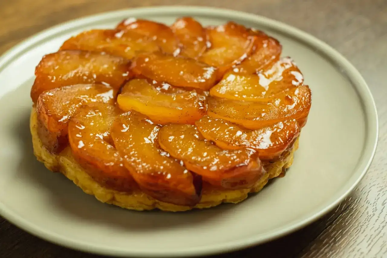 Tarte Tatin inratable : pommes caramélisées et dorées sur une pâte feuilletée croustillante, un délice visuel et gustatif.