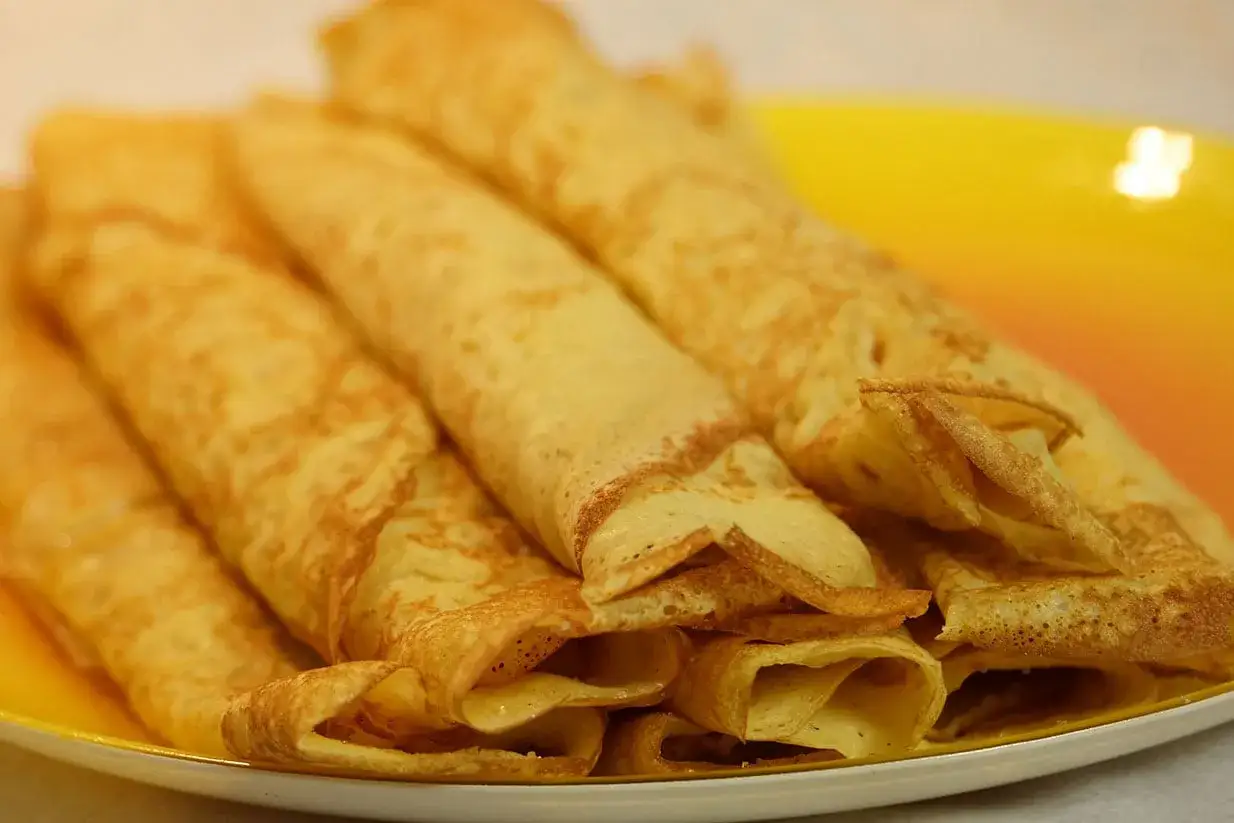 Une assiette de crêpes dorées, roulées et prêtes à être dégustées. Un vrai plaisir pour les yeux et le palais.