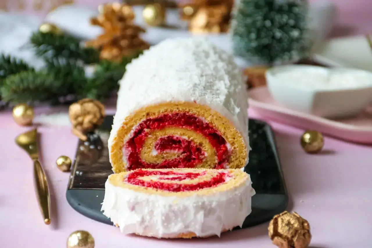 Bûche roulée moelleuse, garnie de framboises et recouverte de noix de coco. Parfaite pour une recette génoise bûche moelleuse festive.