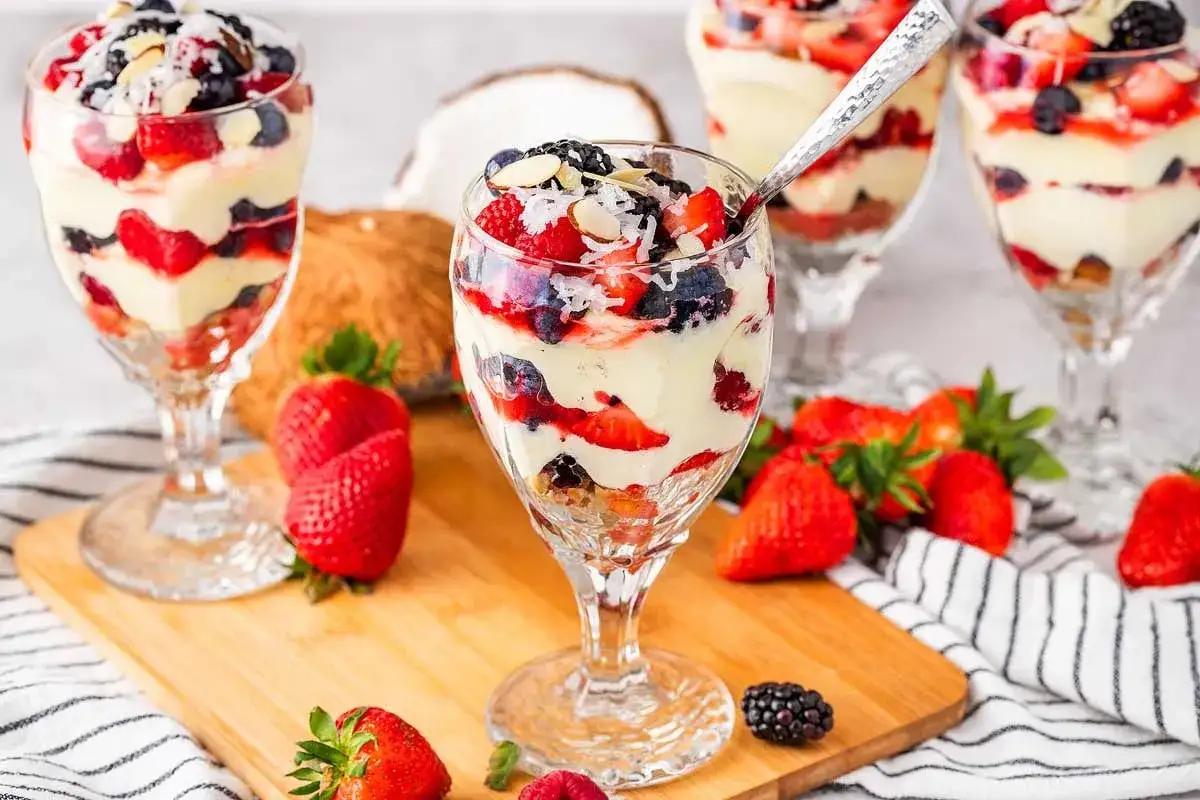 Desserts en verrine avec fruits rouges, crème onctueuse et copeaux de noix de coco. Un délice qui rappelle le curd mangue passion.