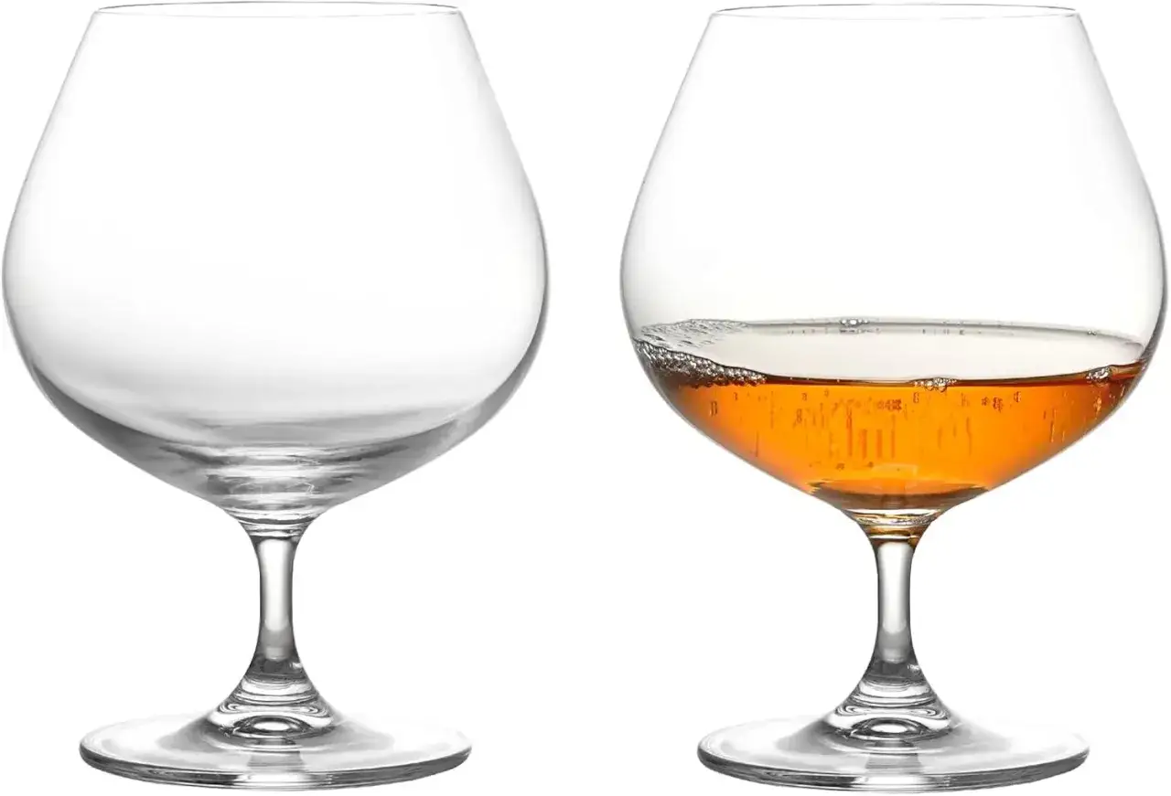 Deux verres à pied, l'un vide, l'autre rempli d'un armagnac digestif ambré aux bulles fines.