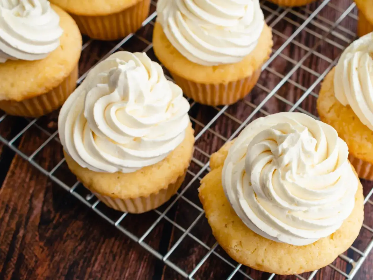Petits gâteaux dorés sur une grille, généreusement garnis d'une délicieuse crème au beurre à la meringue suisse.