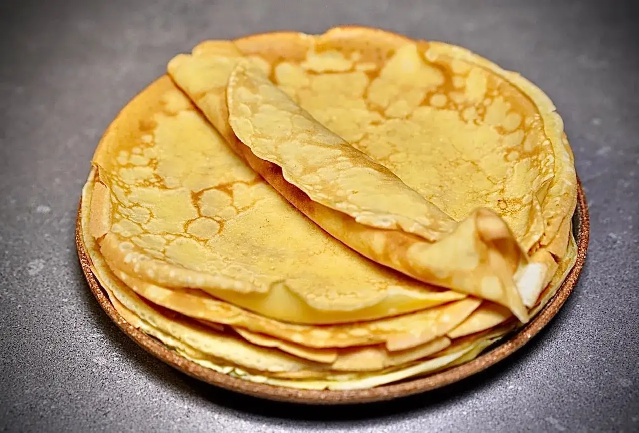 Une pile de crêpes dorées, une est pliée sur le dessus. Un délice à déguster, un vrai patr a crepe !