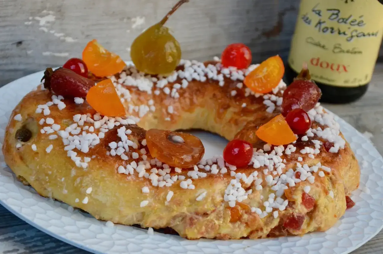 Gâteau des Rois orné de fruits confits et de sucre perlé, prêt à être dégusté.