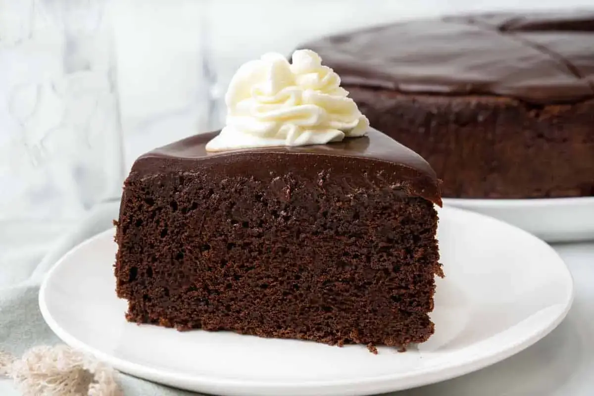 Une part de gâteau au chocolat intense, un vrai délice, avec une touche de crème fouettée sur le dessus. Ce mud cake est irrésistible.