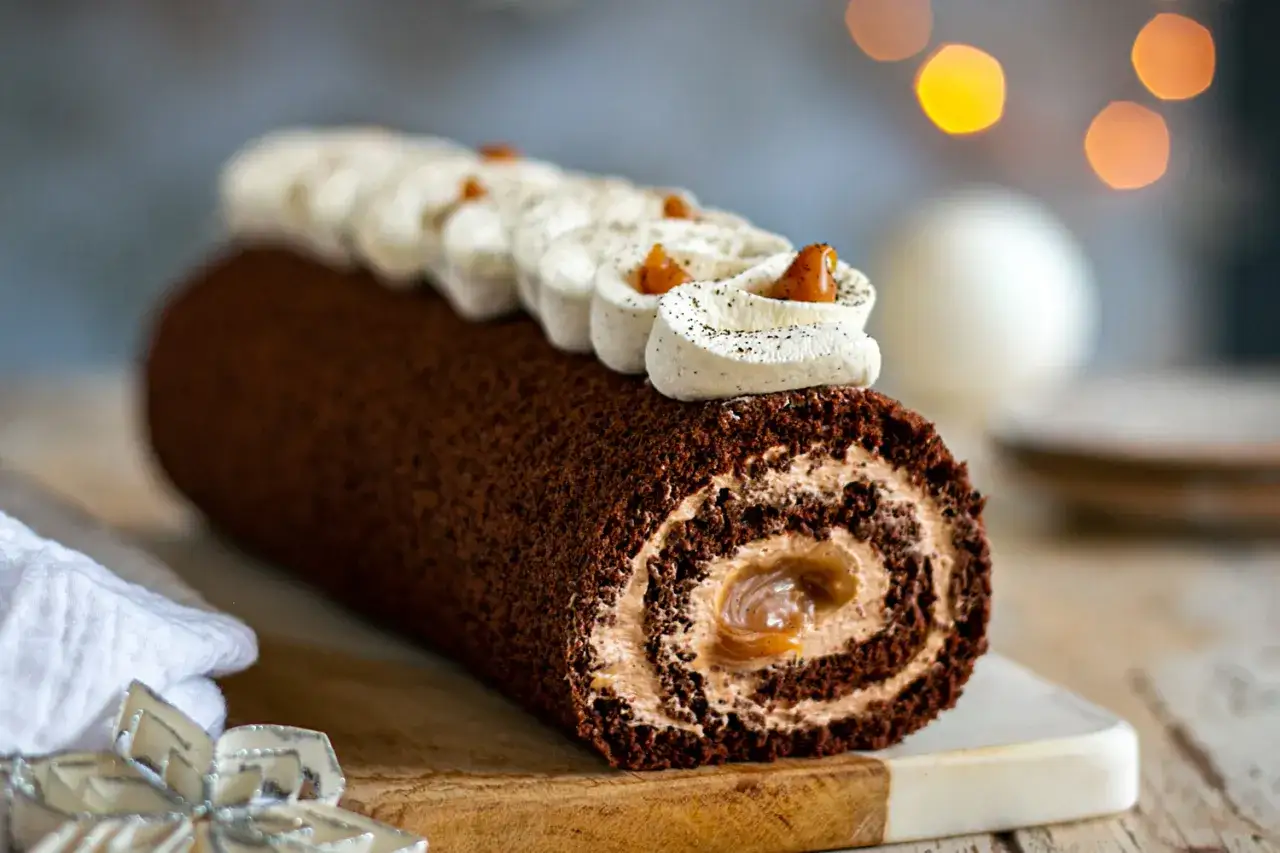 Bûche de Noël au chocolat, garnie de crème onctueuse et de caramel coulant. Une délicieuse recette pour les fêtes.