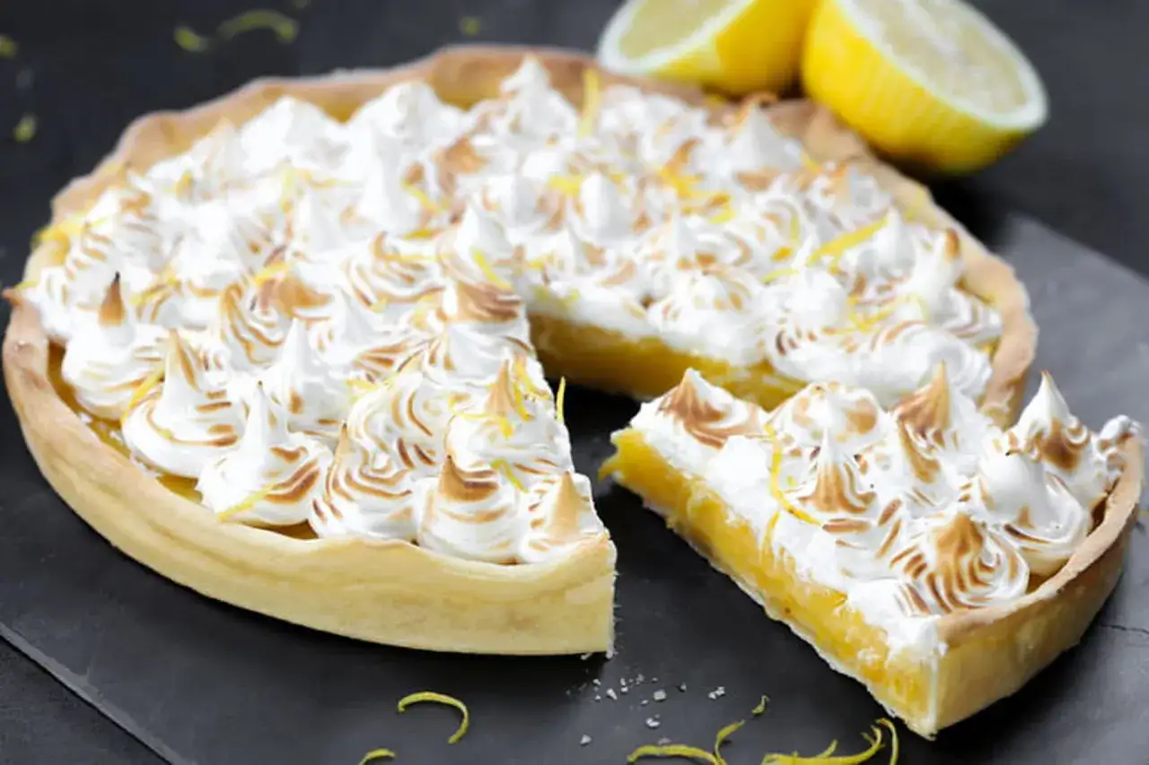 Une délicieuse tarte citron meringuée, avec sa garniture dorée et ses pointes de meringue légèrement caramélisées, prête à être dégustée.