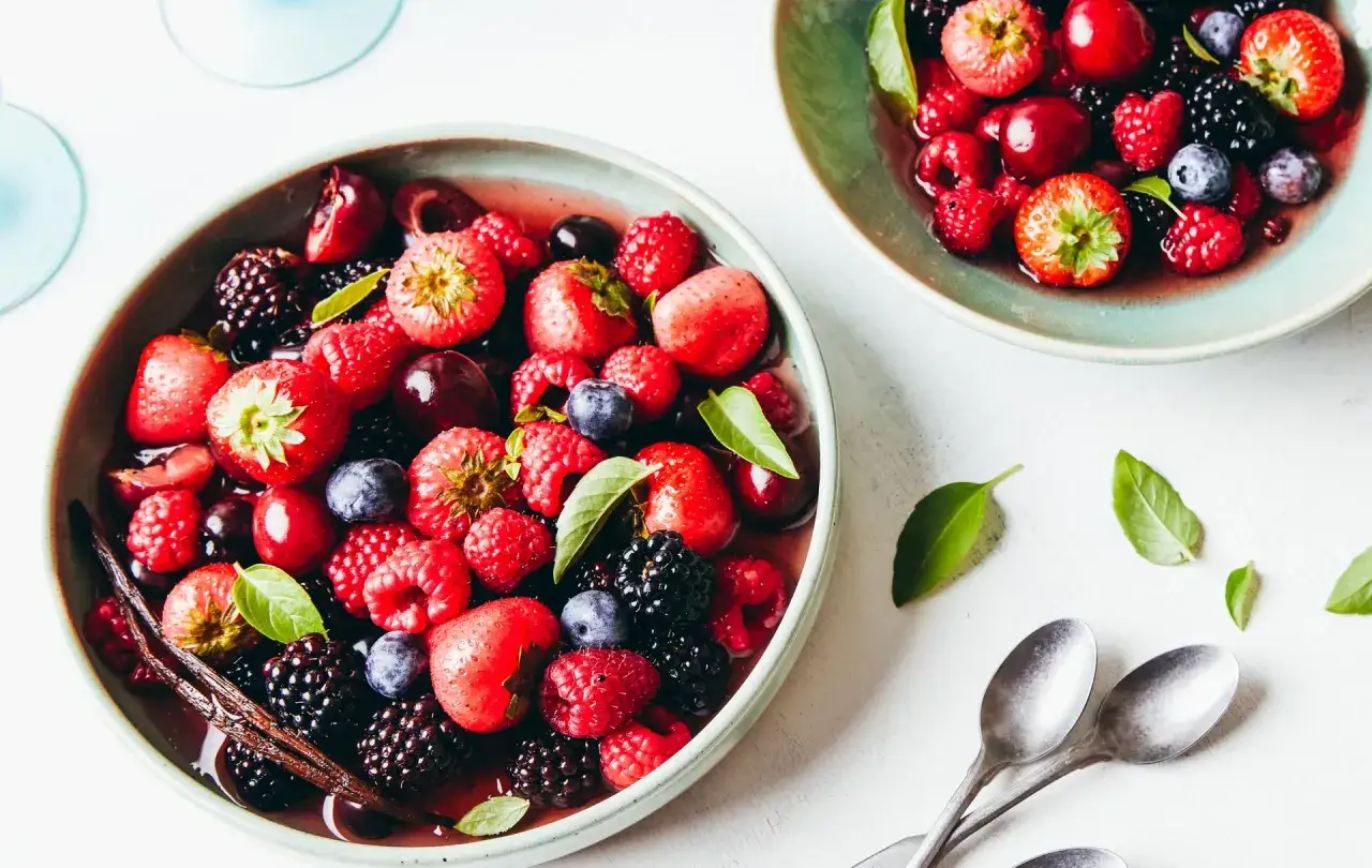 Un délice de fruits rouges et noirs, fraises, framboises, mûres et myrtilles, baignant dans un jus sucré, évoquant un vin fruité.