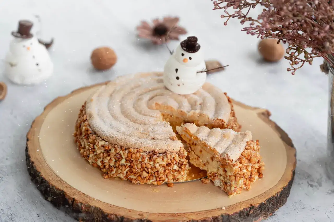 Un délicieux dessert de noël facile et rapide, un gâteau rond couvert de noisettes concassées et décoré d'un petit bonhomme de neige.