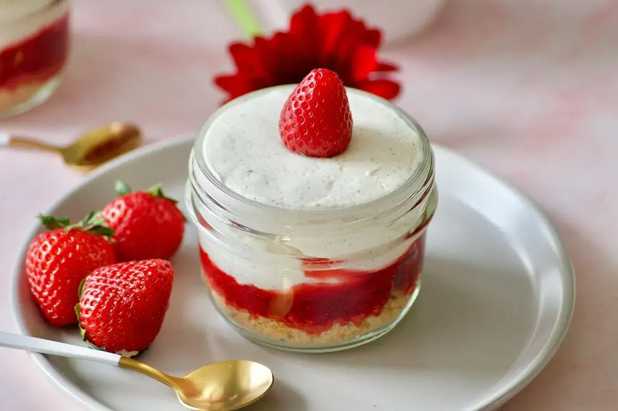 Délicieux tiramisu sans oeuf aux fraises, présenté en pot avec une fraise fraîche sur le dessus.