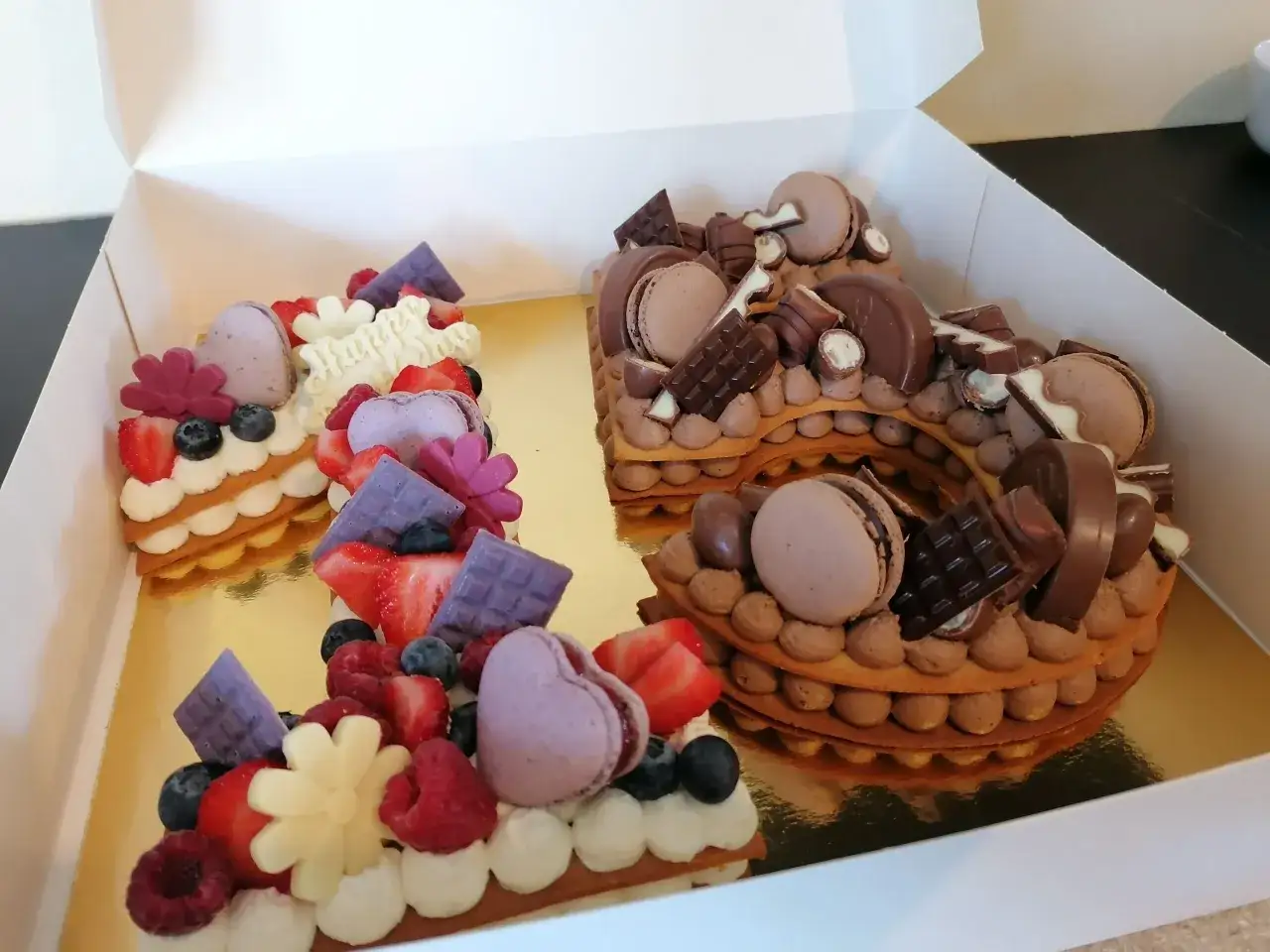Deux number cakes, l'un aux fruits rouges et l'autre au chocolat, décorés de macarons, chocolats et fruits. Un délice pour un anniversaire !