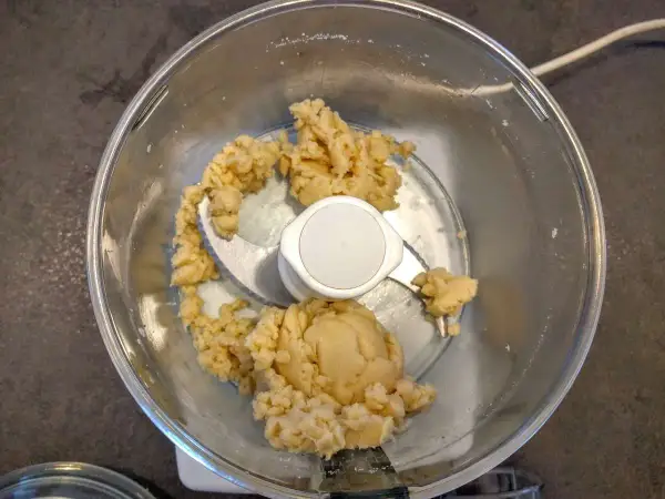 Pâte d'amande maison dans un robot culinaire, prête à être façonnée en délicieuses friandises.