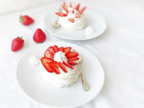 Deux pavlovas ornés de fraises et de crème fouettée, une touche de curd mangue passion pour l'exotisme.